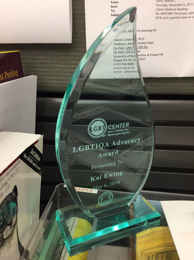 Teardrop-shaped translucent award with the words, "LGBTIQA Advocacy Award Presented To Kai Ewing May 6, 2018" and the LGBTQ Center's logo